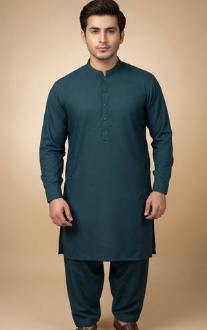 Man wearing a teal long-sleeve shirt and dark pants on a beige background