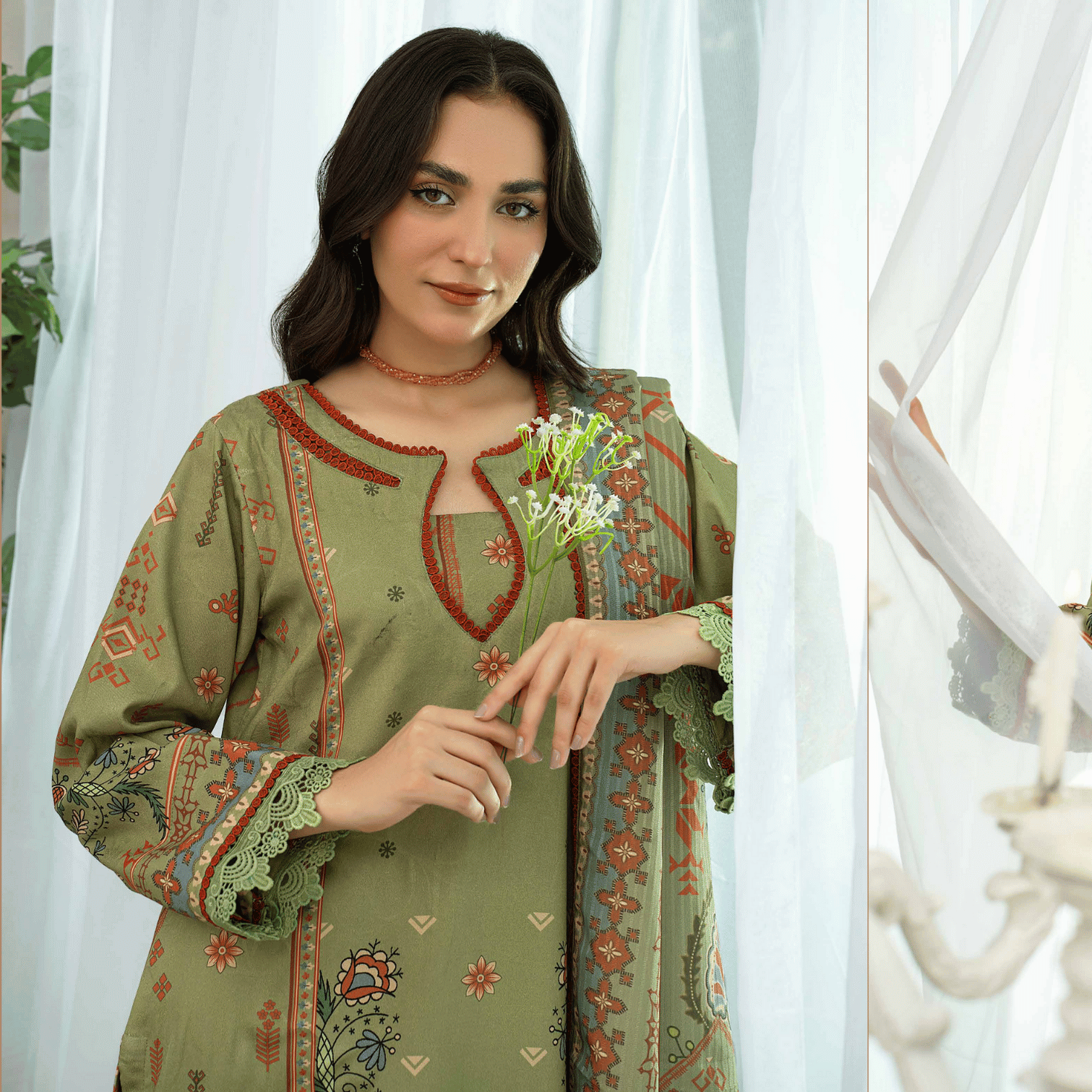 Woman wearing a green embroidered traditional outfit with a white curtain background