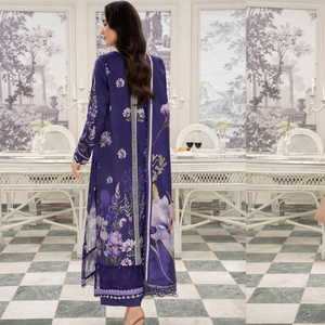 Woman in a blue floral dress standing in a room with white furniture and large windows.