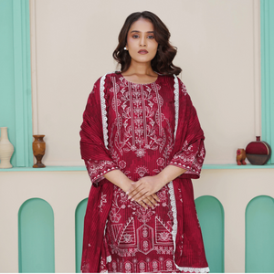 Woman wearing a red embroidered traditional outfit in a decorative setting.