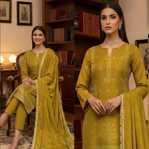 Woman in a mustard yellow traditional outfit standing in a room with wooden furniture.