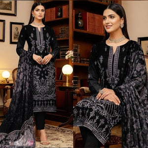Woman in a black embroidered traditional outfit sitting in a room with decor.
