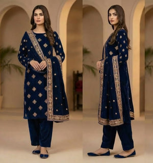 Woman in a blue embroidered traditional outfit standing in front of arches.