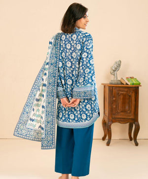 Woman wearing a blue embroidered outfit with a matching dupatta in a room setting.
