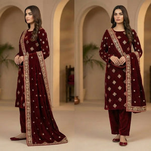 Woman in a maroon traditional outfit with intricate patterns in a decorative setting.