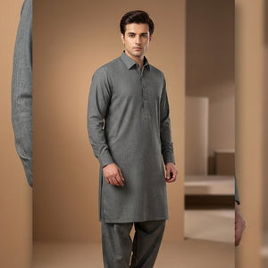 Man wearing a gray kurta standing in a neutral-colored room.