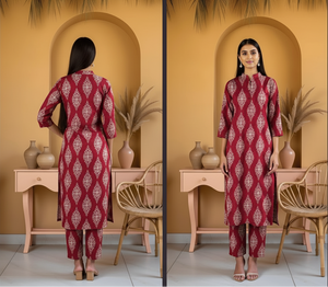 Woman wearing a red patterned outfit standing in front of a decorative wall with vases and plants.