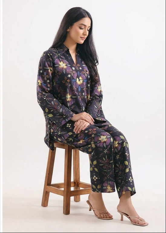 Woman sitting on a wooden stool wearing a floral pajama set against a white background