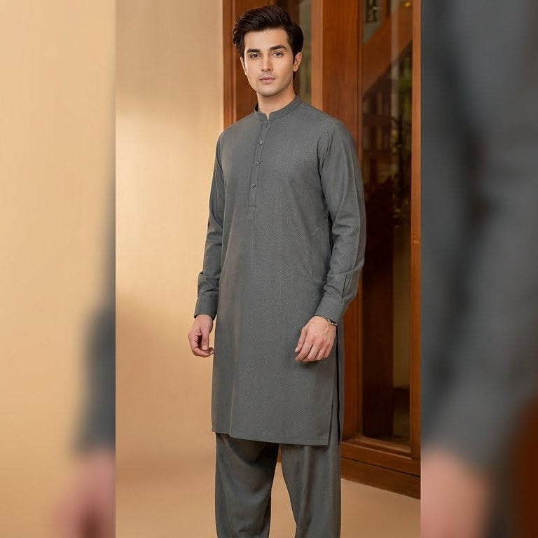 Man wearing a gray kurta standing in front of a wooden door.