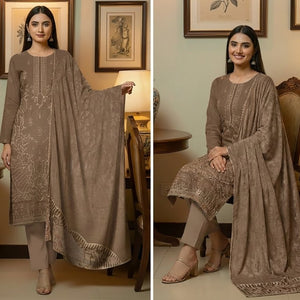 Woman modeling a brown embroidered traditional outfit in a home setting.
