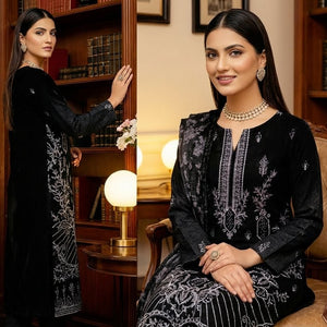 Woman in a black and gray traditional outfit sitting in a room with bookshelves and a lamp.
