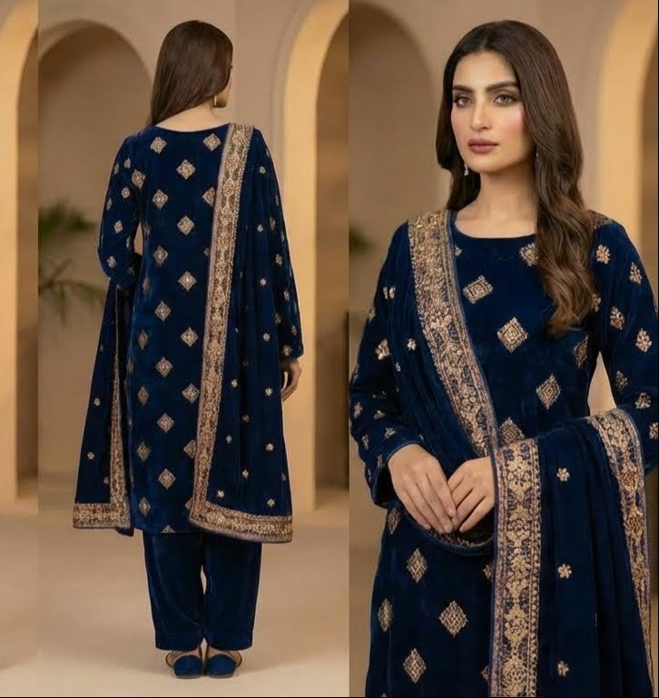 Woman modeling a blue embroidered traditional outfit in an indoor setting with arches.