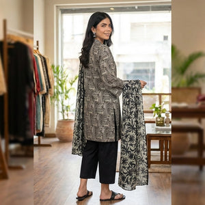 Woman holding a patterned outfit in a clothing store.