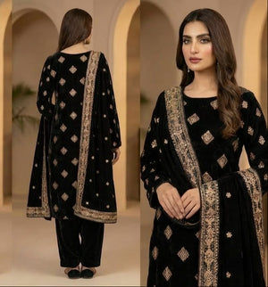 Woman in a black traditional outfit with gold embroidery in a beige archway setting