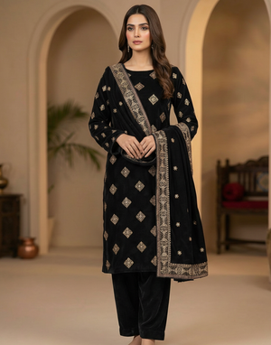 Woman wearing a black traditional outfit with intricate patterns in a warm-toned room.