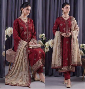 Woman in a red and beige traditional outfit with floral decorations against a gray curtain background.