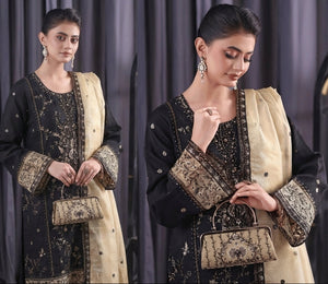 Woman in traditional outfit with jewelry and handbag against a plain background