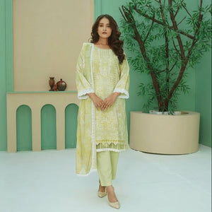 Woman in a light green traditional outfit standing in a minimalistic room with a plant and decorative items.