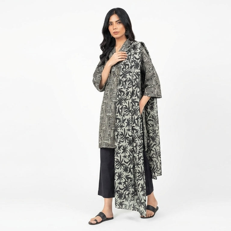 Woman wearing a long, patterned coat over a black outfit on a white background